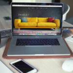 Ordinateur portable Mac ouvert avec un fond d'écran moderne de canapé