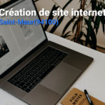 Ordinateur portable sur un bureau derrière une plante avec un texte : Création de site internet à Saint Maur Des Fossés