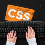 Un clavier d'ordinateur noir et un chiffon orange inscrit CSS (Cascading Style Sheets)