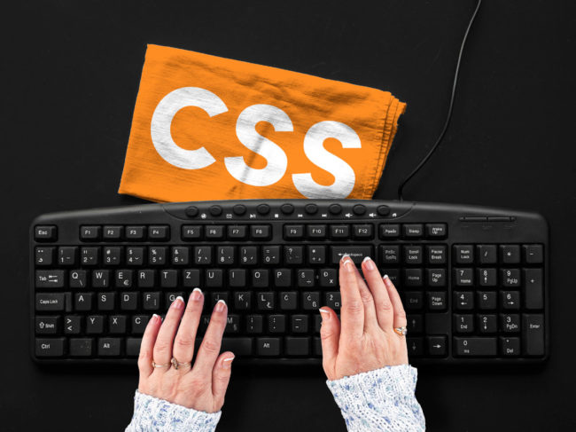 Un clavier d'ordinateur noir et un chiffon orange inscrit CSS (Cascading Style Sheets)